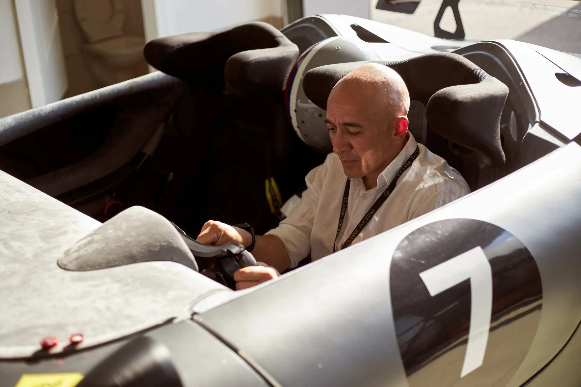 A cockpit fitting: a man lowering himself into the open car